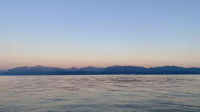 The Alps turning pink before sunset with the lake in front