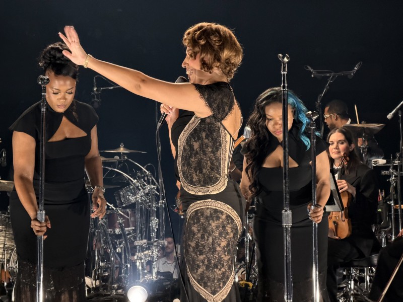 RAYE calling out with her left arm smiling
