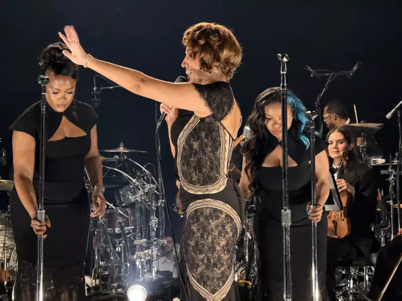 RAYE calling out with her left arm smiling