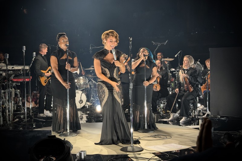 Front view of the set with RAYE in the middle, back vocals, lead guitar and strings behind