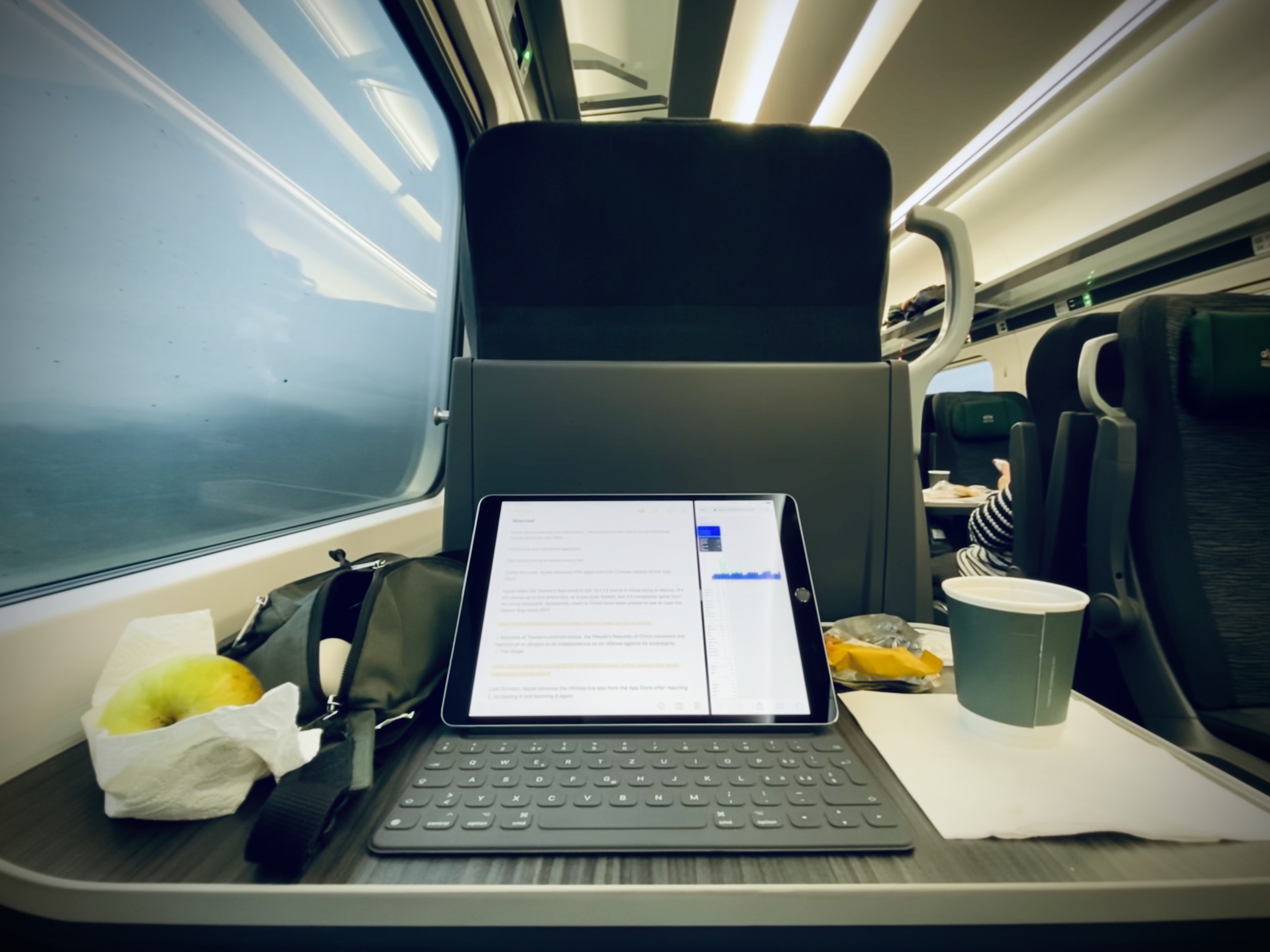Tray table with an iPad and coffee mug facing the direction of travel