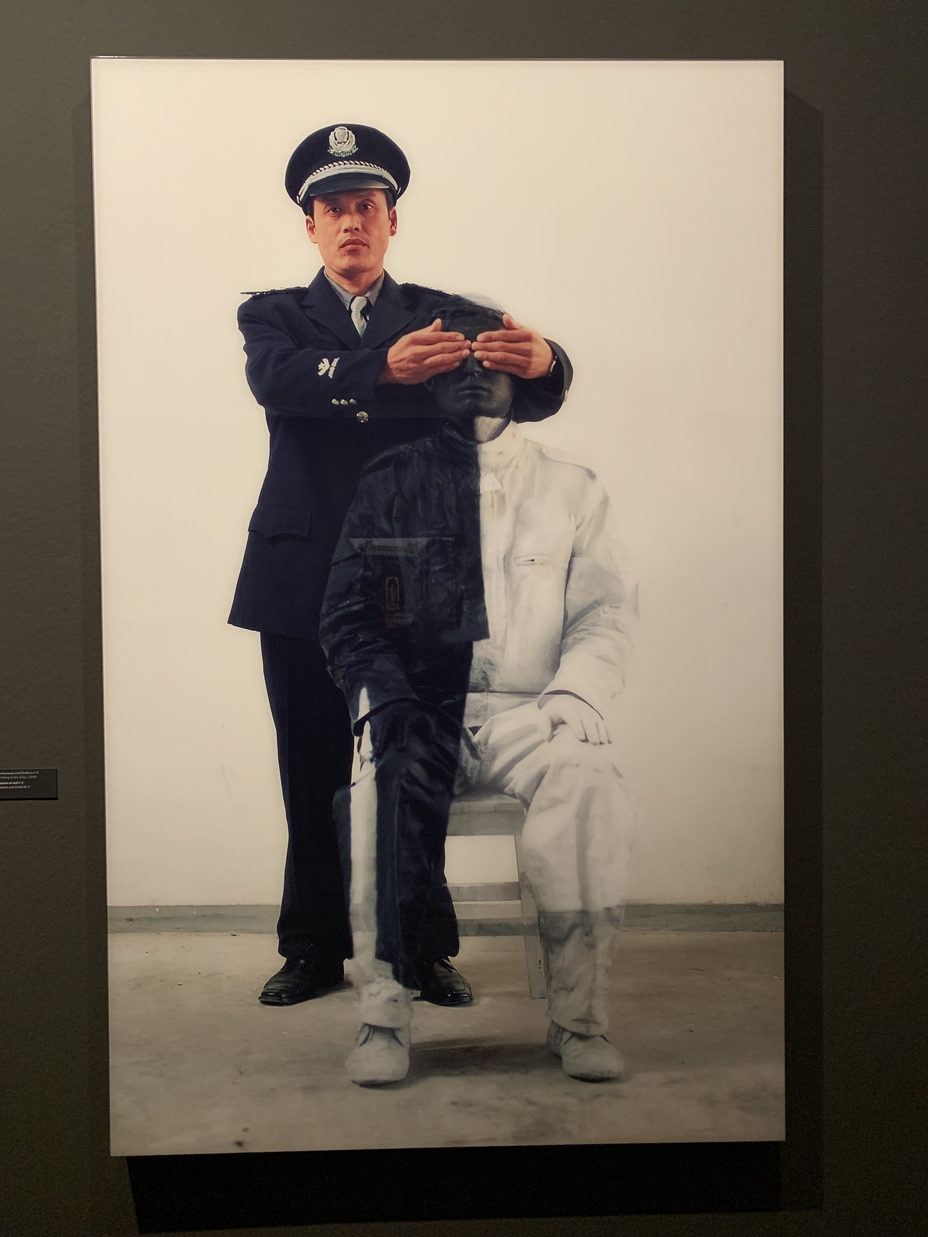 A police officer masking Liu Bolin's eyes