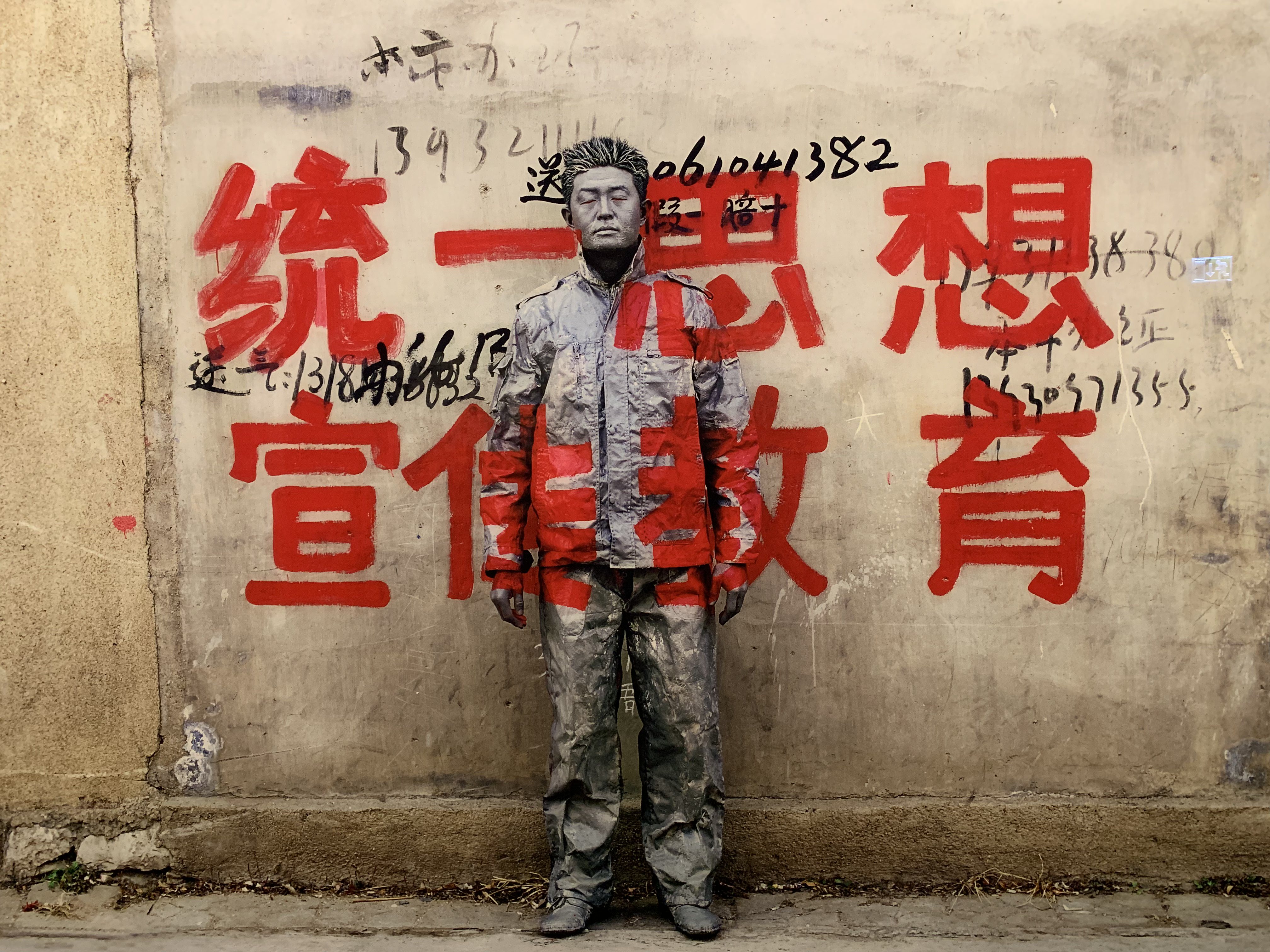 Liu Bolin painted in a wall with graffiti