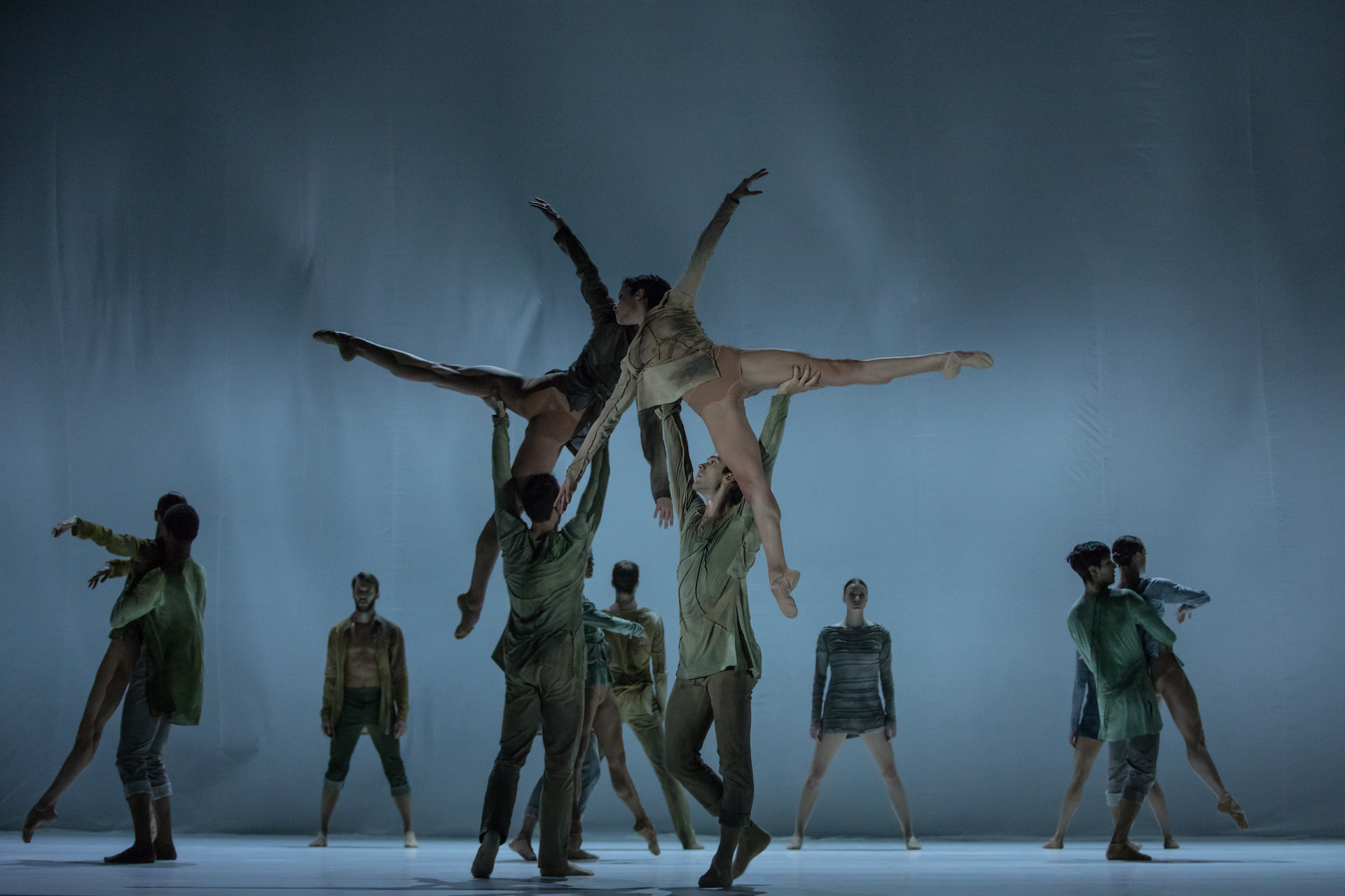 Porté. Male dancers carrying their partners through the stage on a blue background. Photo by Gregory Batardon.