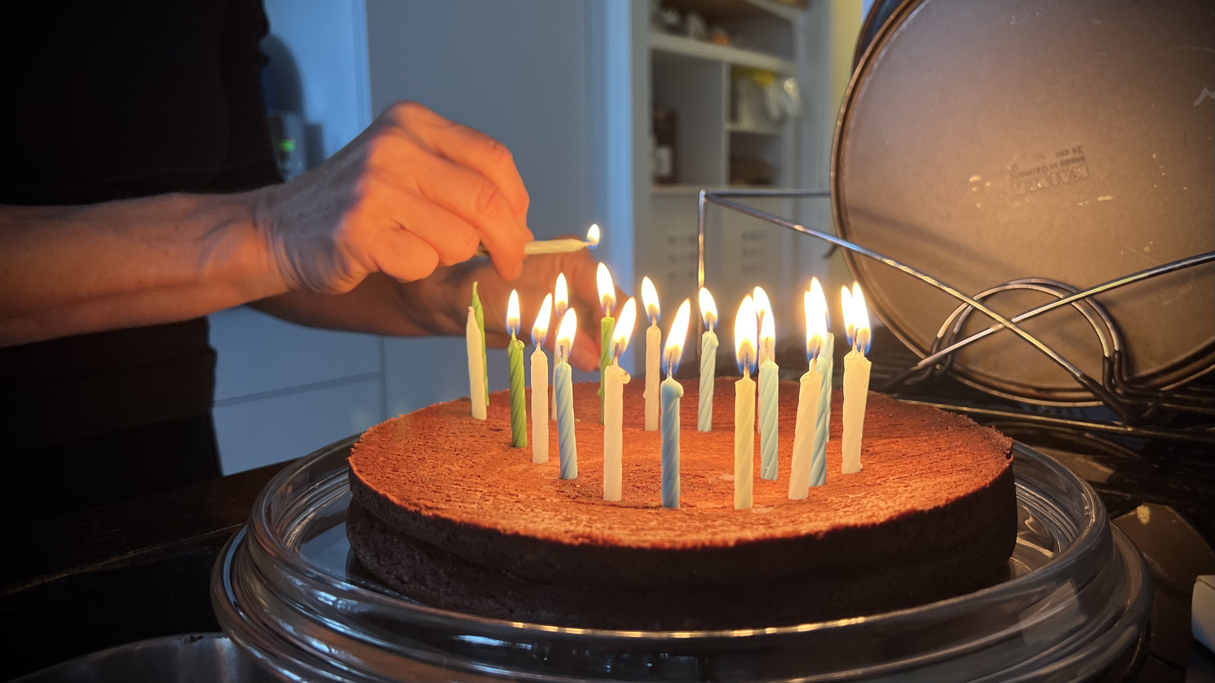 A chocolate cake with 21 coloured candles being lit by Fabienne