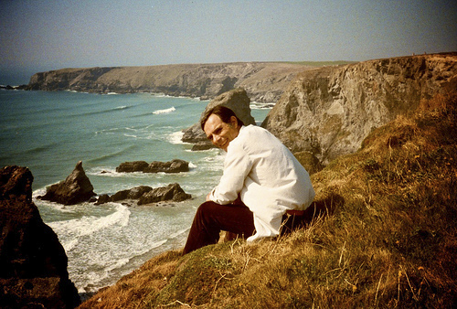 Dad smiling sitting on a cliff facing the ocean around Land's End in Cornwall, UK