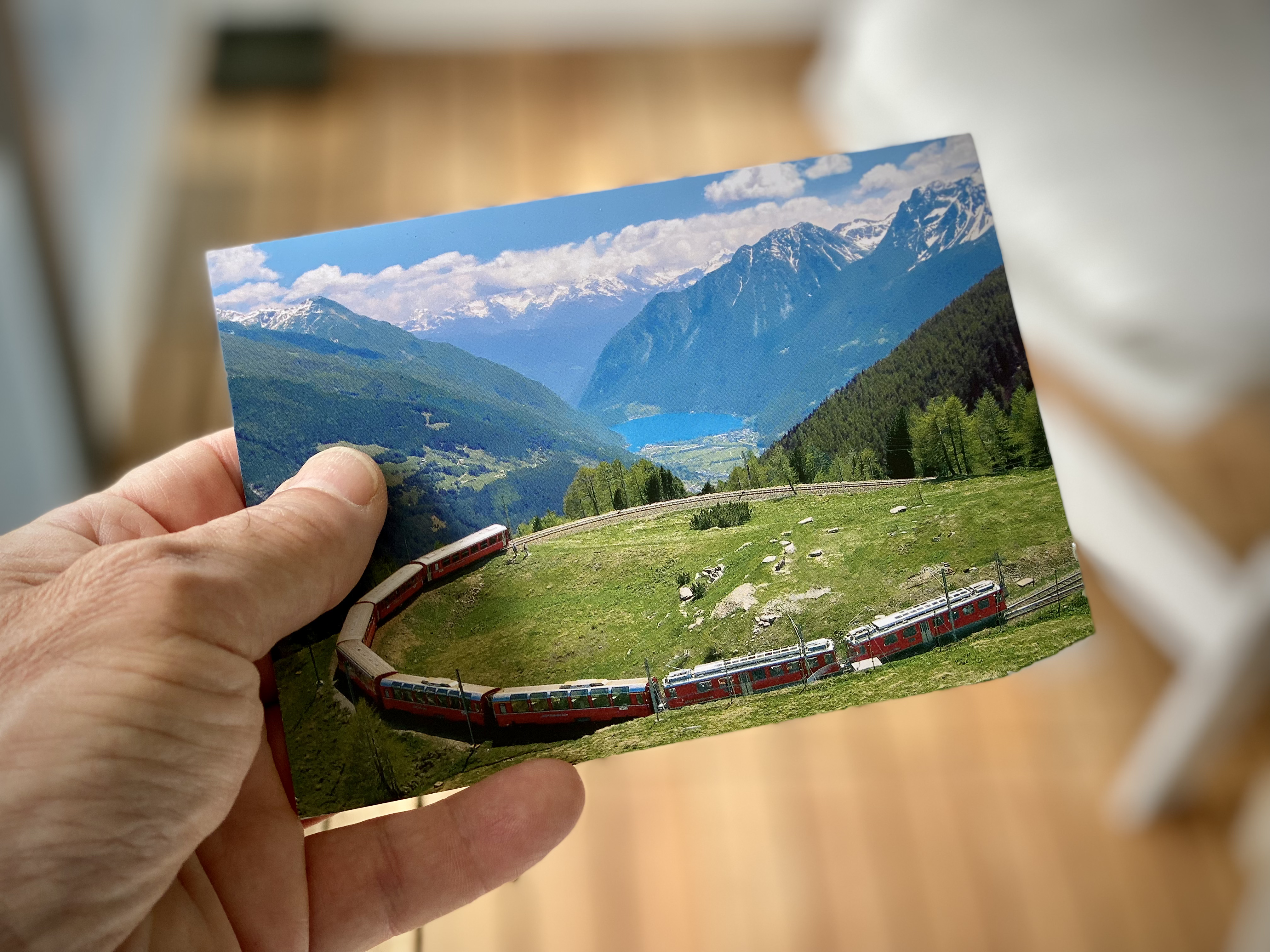 Postcard with a red train running up a mountain