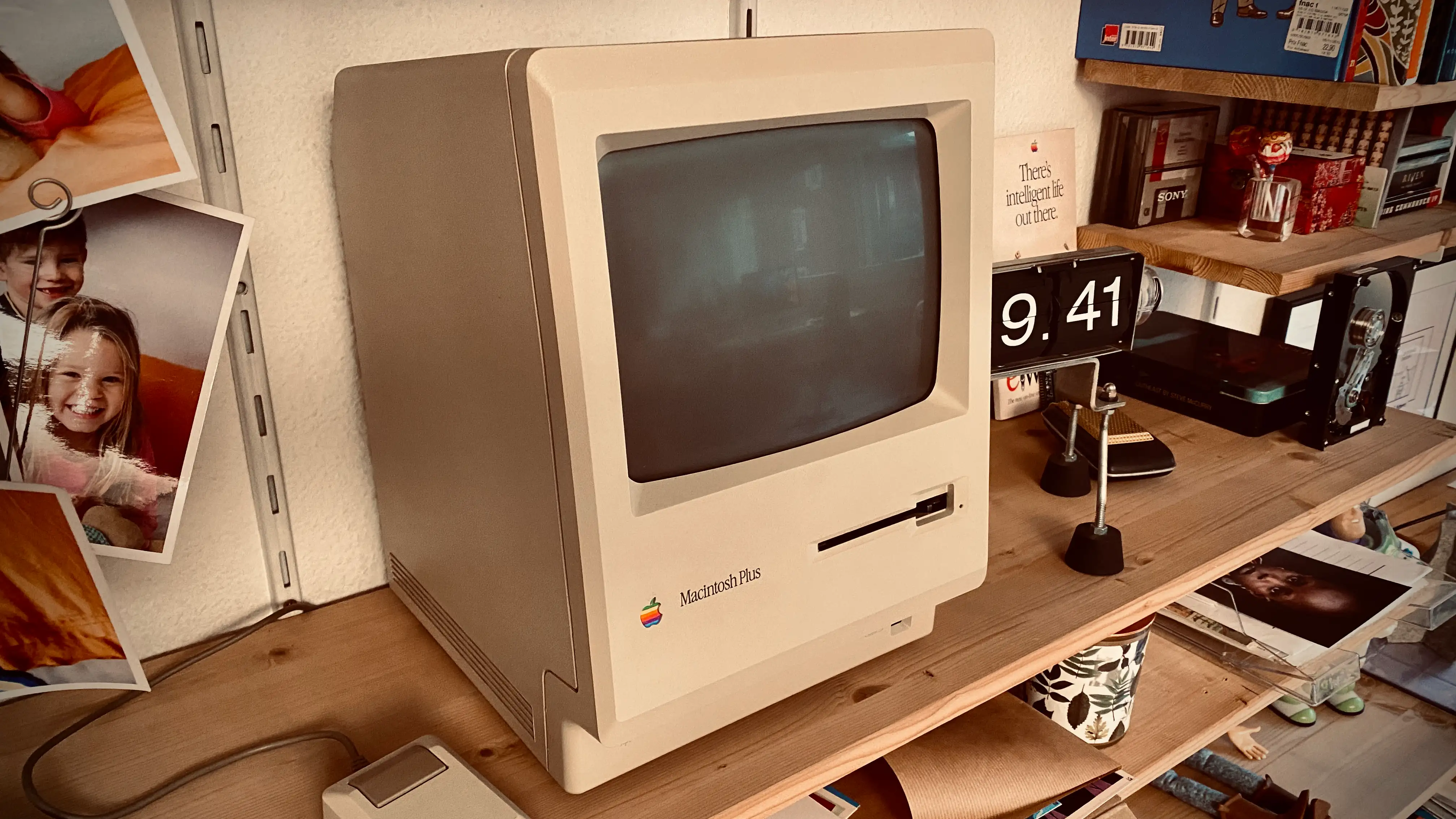 Mac Plus 512 sitting on my bookshelf in my office with an analog number clock on it's right stuck on 09:41